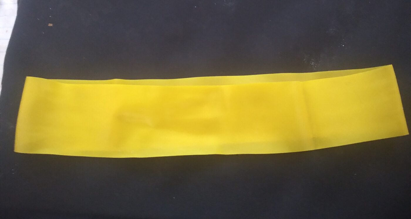 A flat yellow latex resistance band laid out on a dark surface.