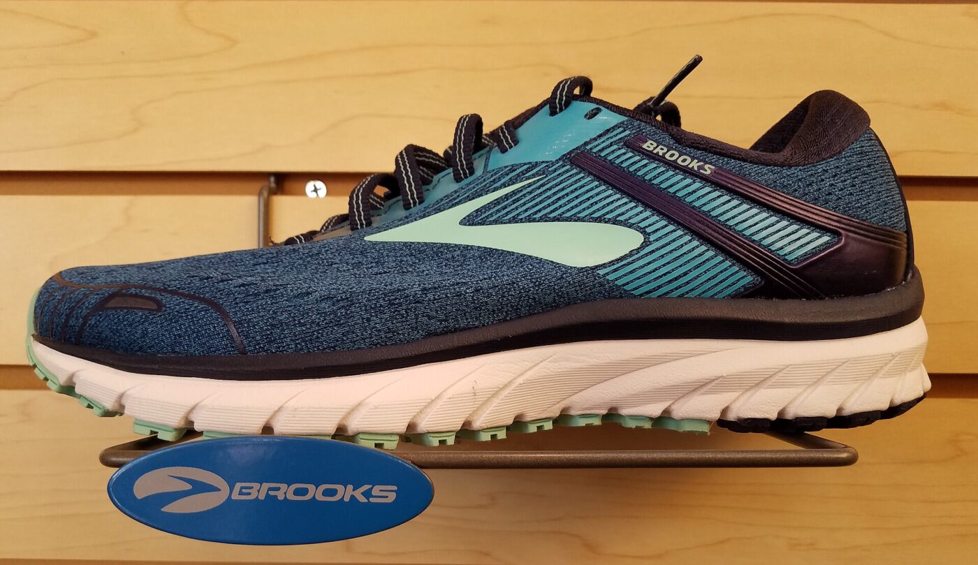 A blue and teal Brooks running shoe displayed on a store wall shelf