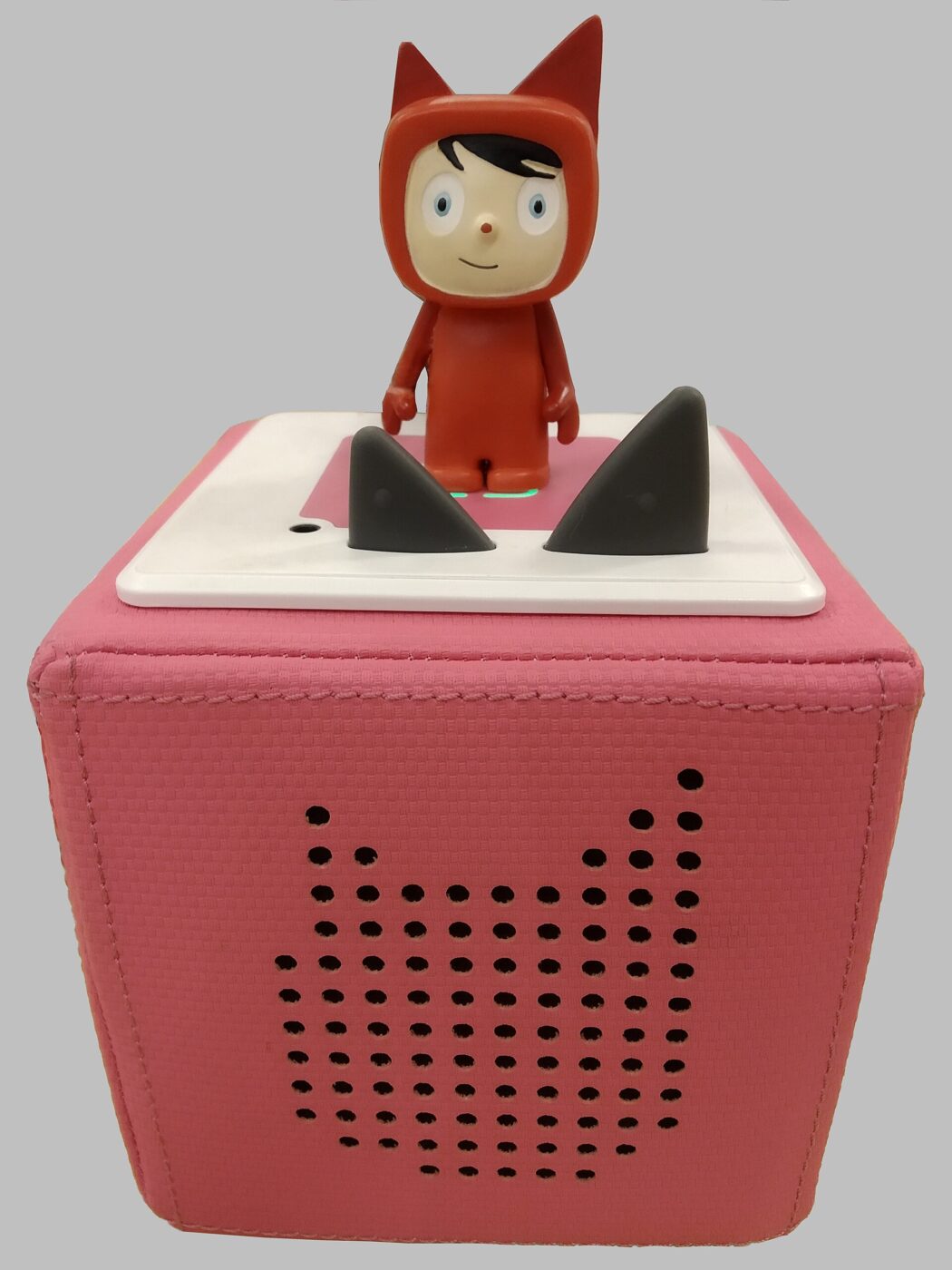 A red cube-shaped kids' audio player with cat-ear buttons and a character figure on top