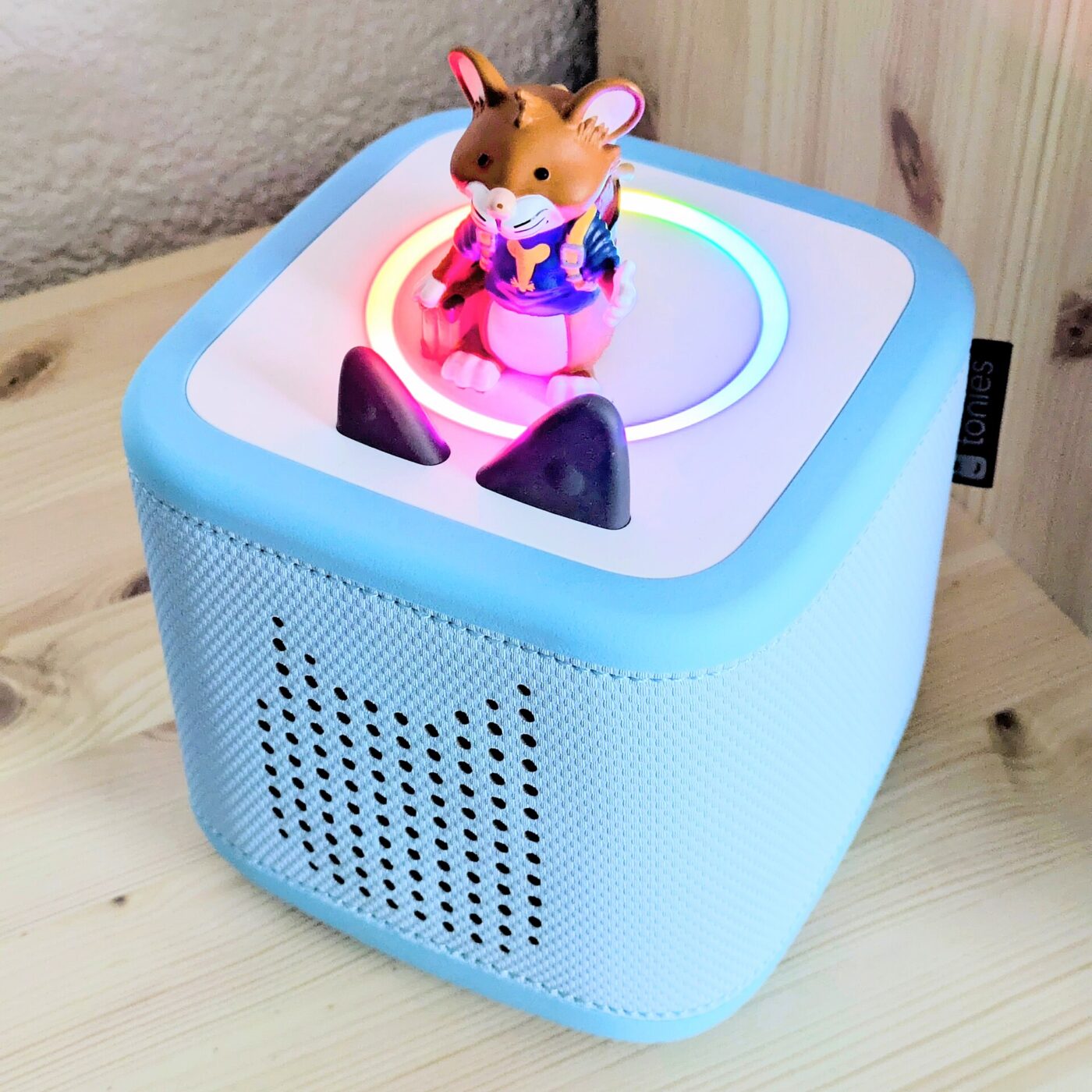 A light blue Toniebox with a character figure on top and a glowing light ring