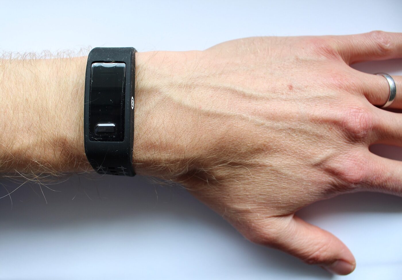 A black fitness band with a dark, blank face worn on an adult's wrist