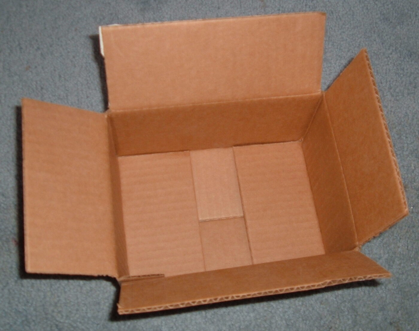 An empty corrugated cardboard shipping box with its flaps folded open.