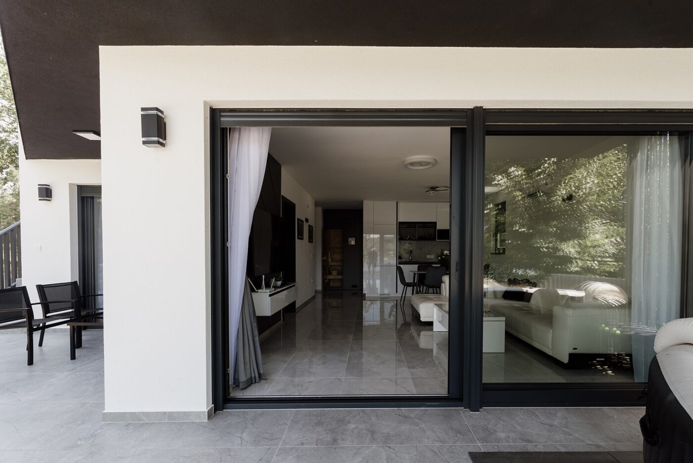 A patio slider standing open between a tiled living room and an outdoor terrace.