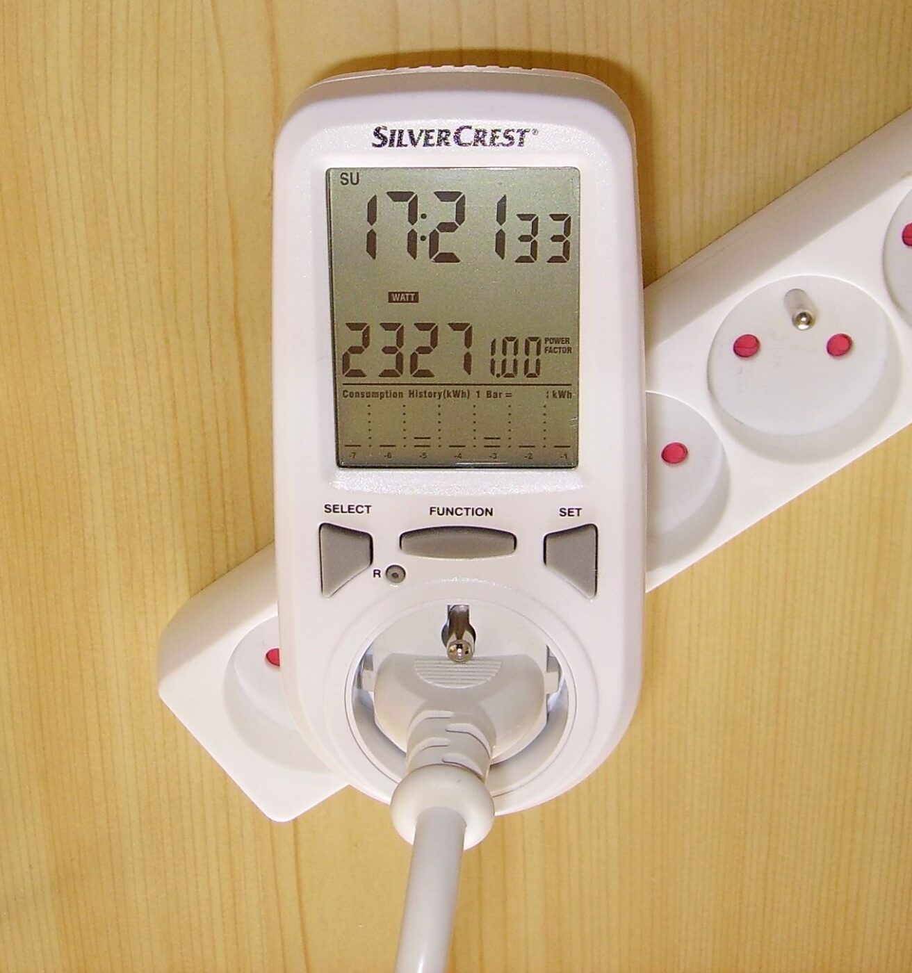 A plug-in energy monitor in a wall socket showing elapsed time and kilowatt-hours used.