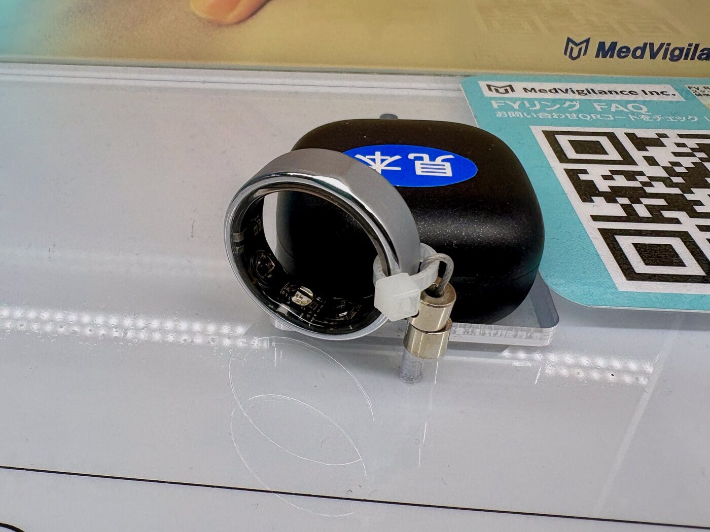 Store sample of a silver smart ring, with sensors visible on its inner side, tethered to a display