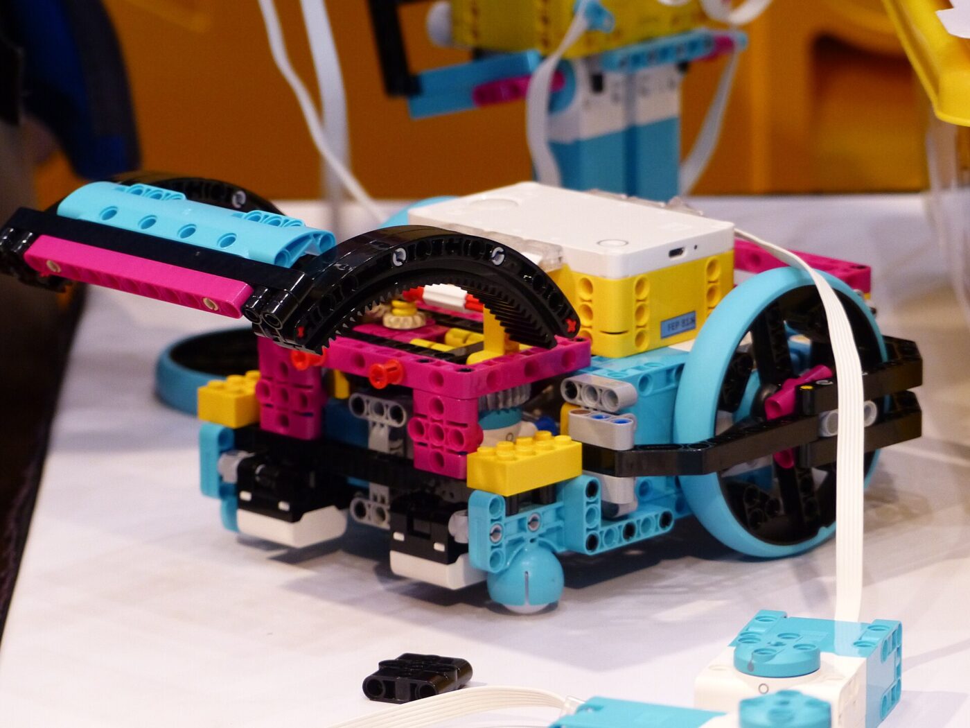 A wheeled robot built from colorful plastic bricks around a programmable hub on a table