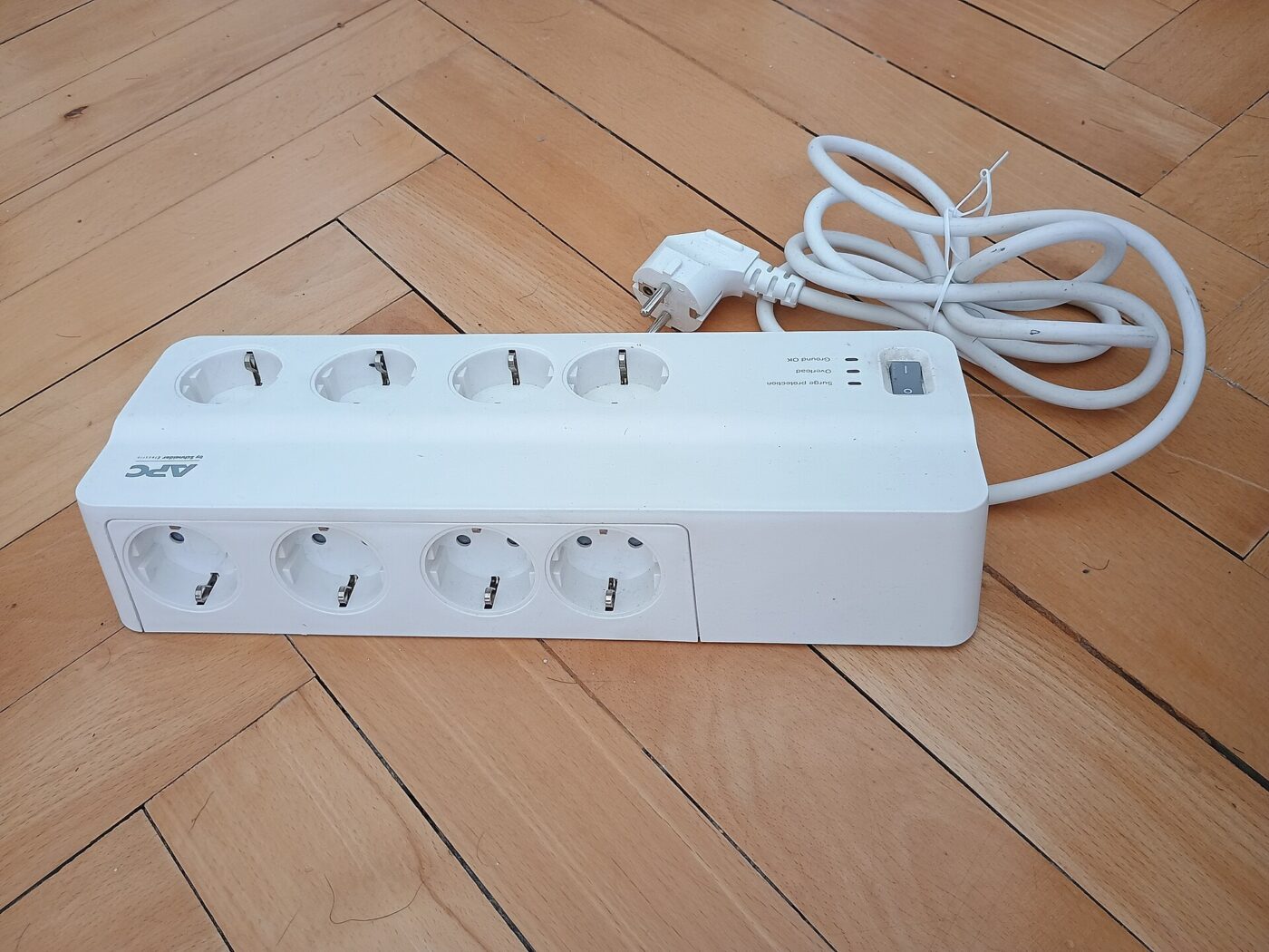 A white power strip with four outlets, an on-off switch and a long cord