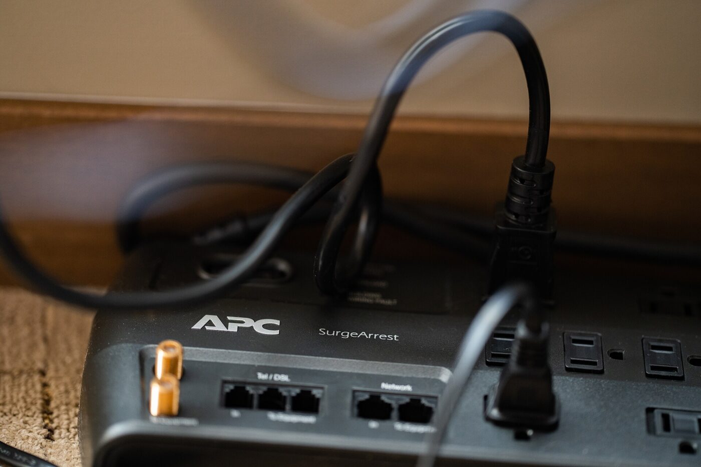 A surge protector strip in use, with plugs inserted and phone and network jacks on its face