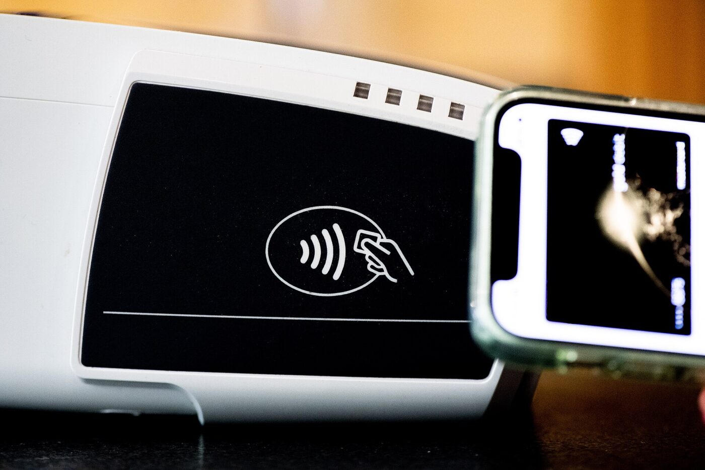 A smartphone held against a contactless card terminal to complete a payment
