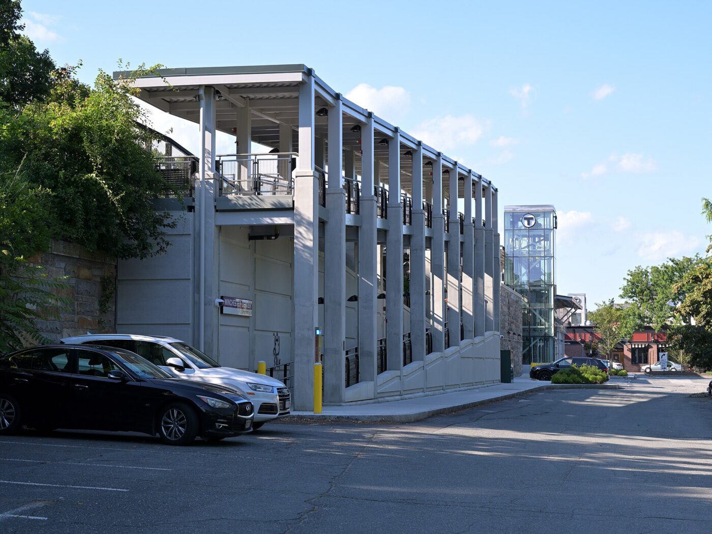 A long wheelchair ramp runs beside a commuter rail platform next to a glass elevator.
