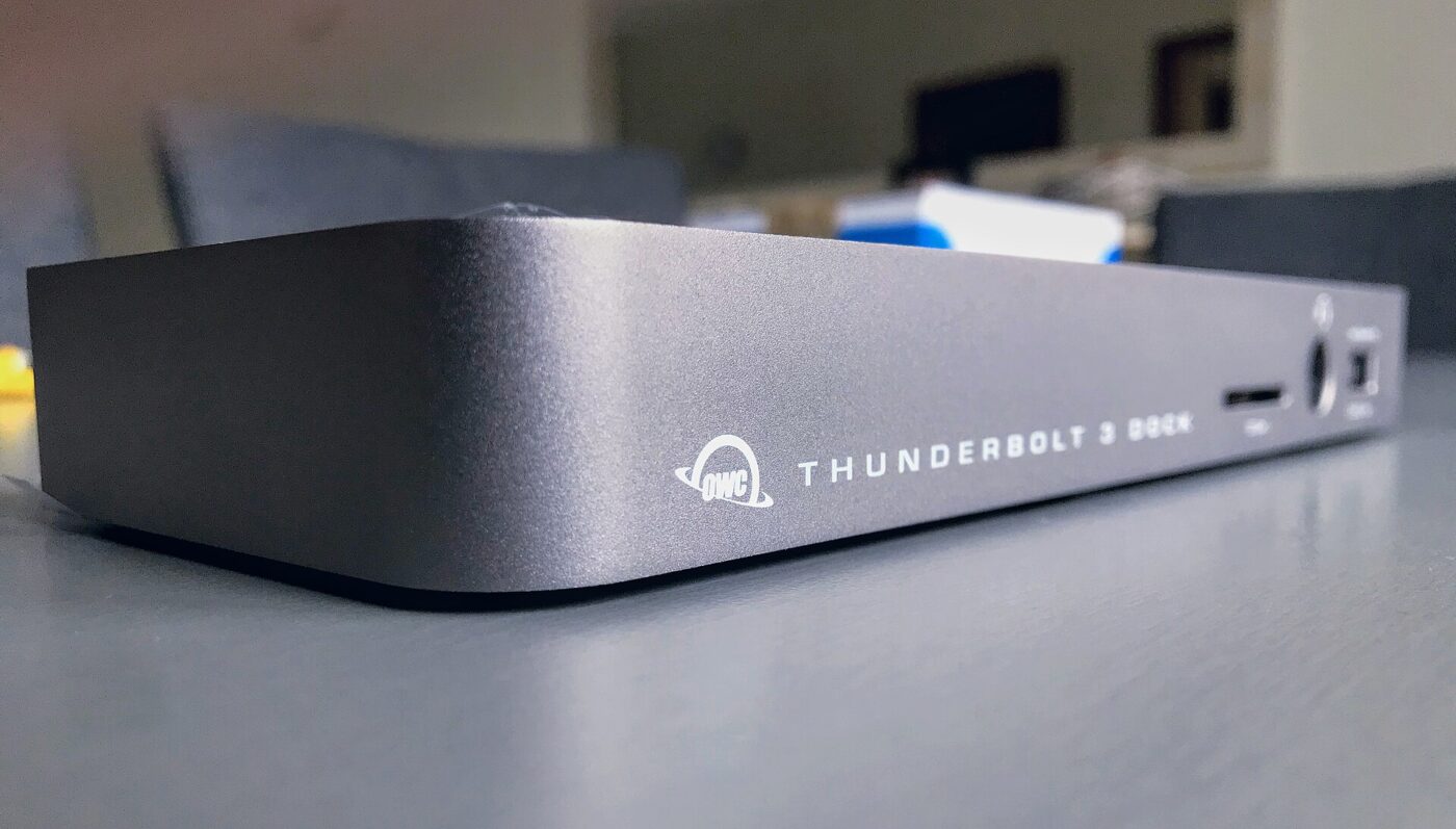 A gray Thunderbolt 3 docking station on a desk, with a card slot and ports on its front