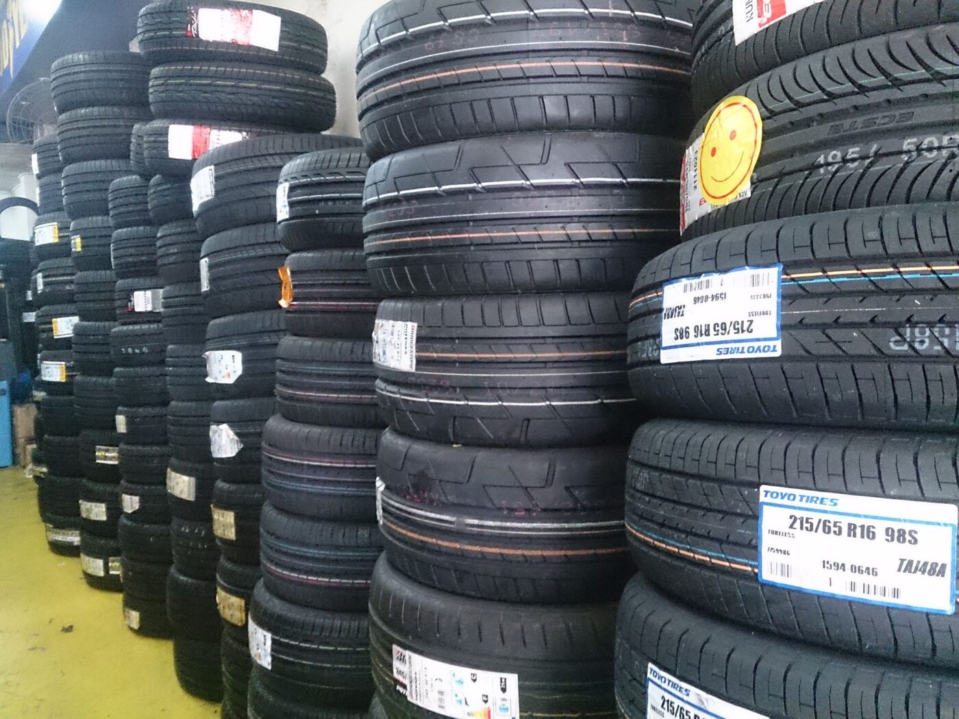 Stacks of new car tires with size labels on their treads in a tire shop