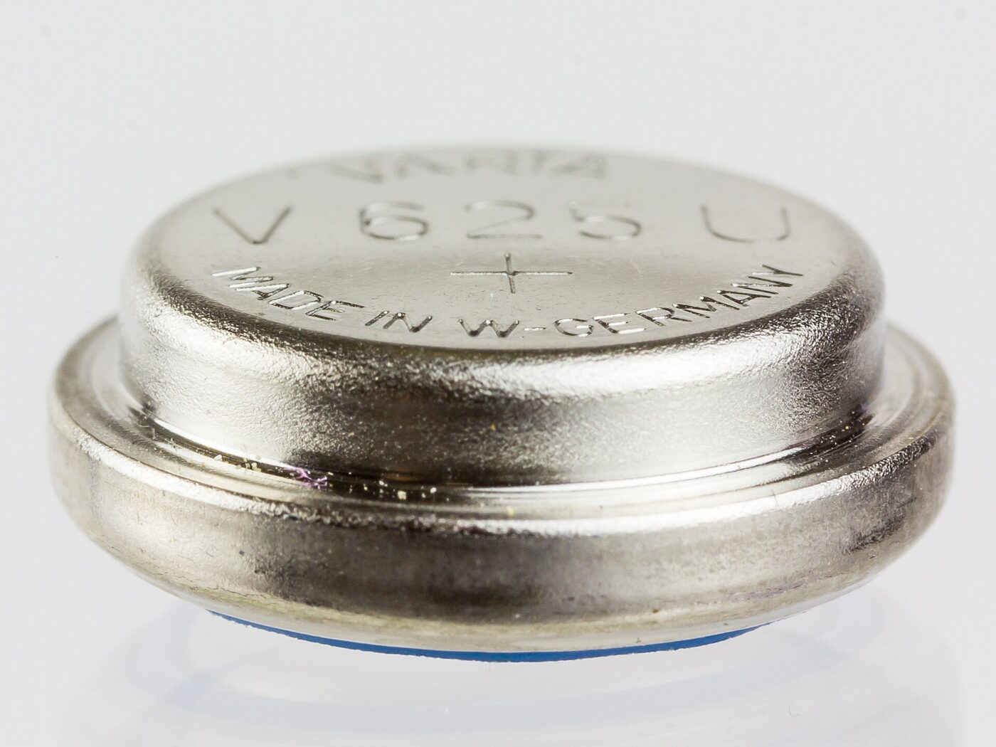 A silver button cell battery photographed against a plain white background.