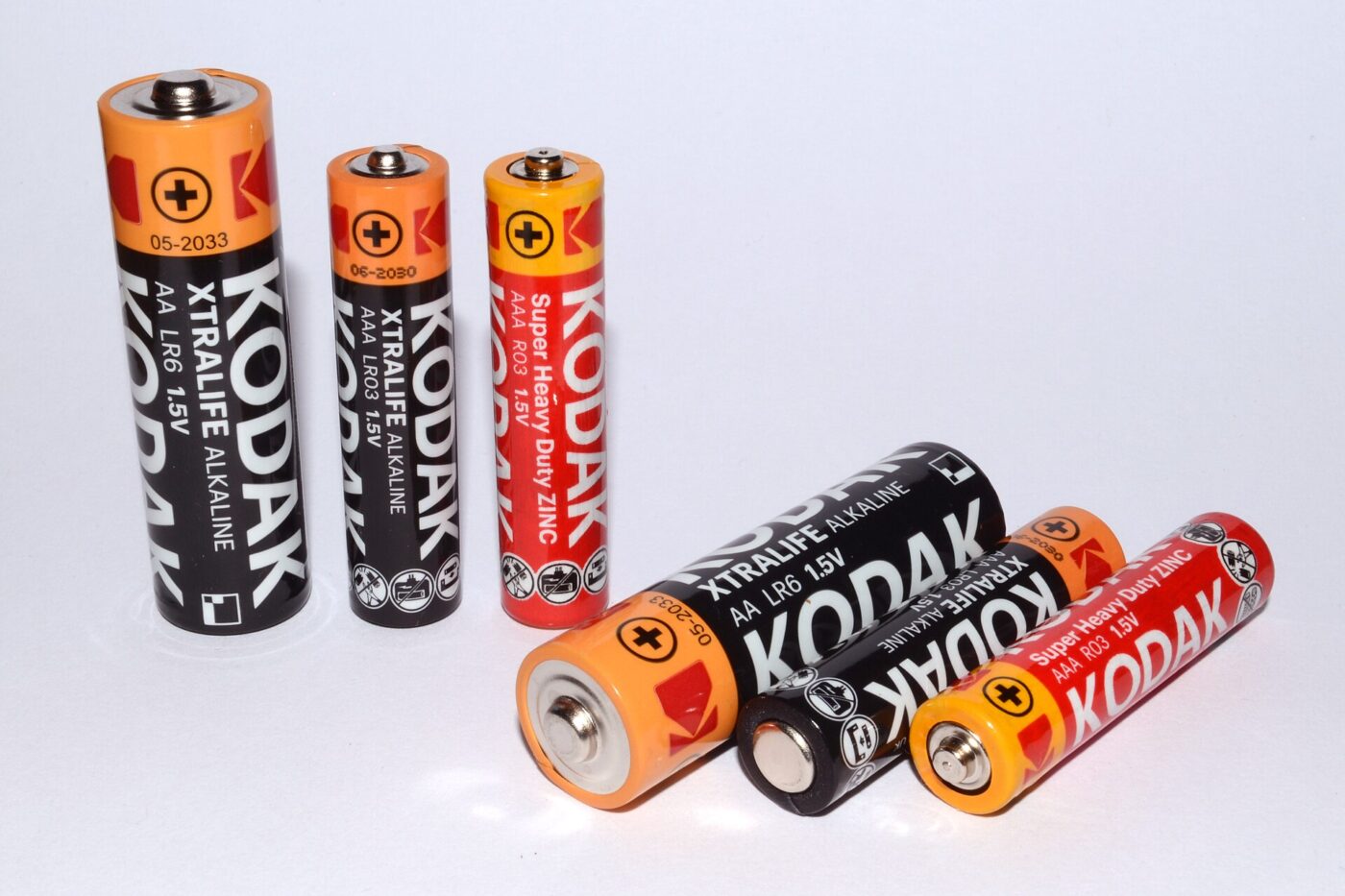 Six AA and AAA batteries, some standing upright and some lying, on white.