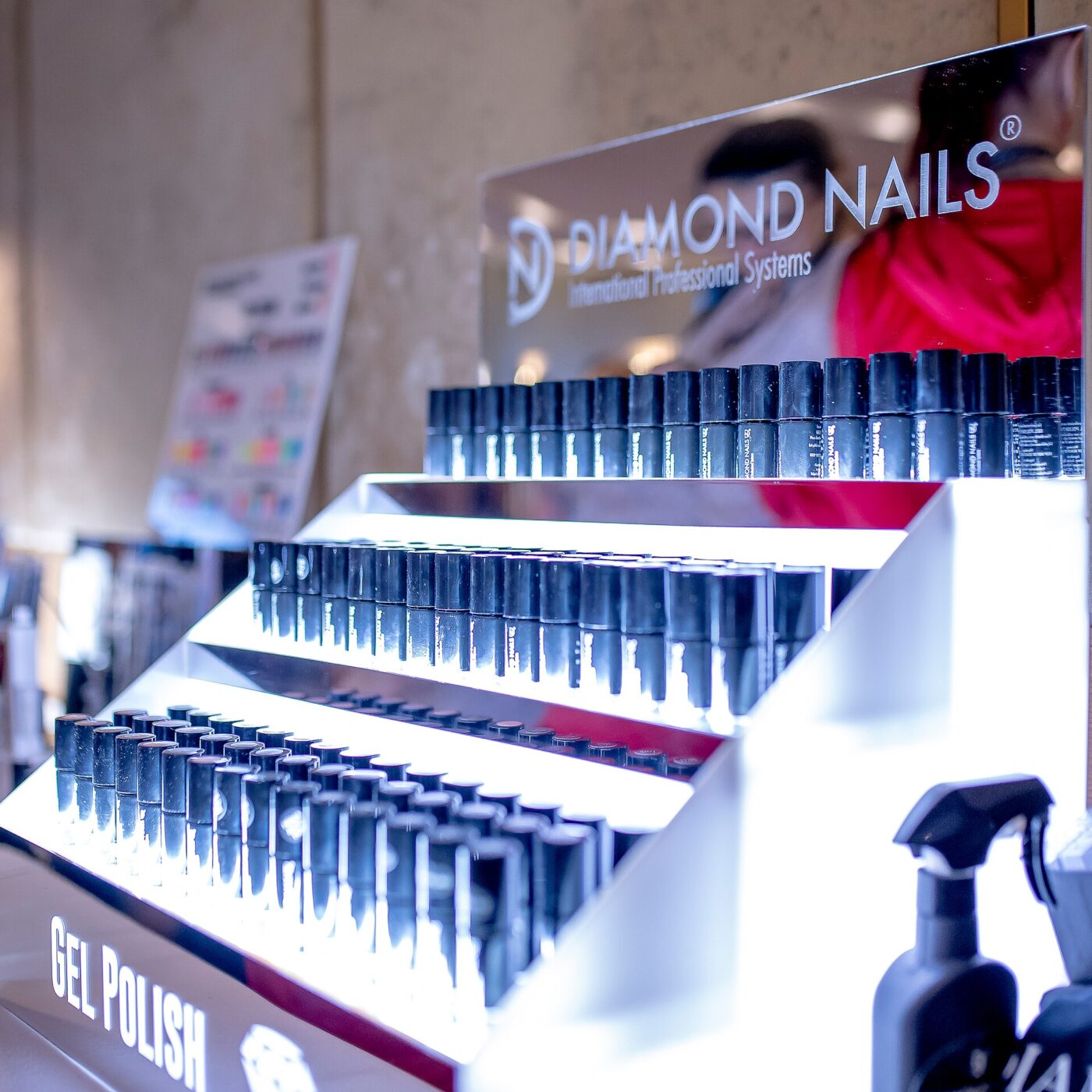 Rows of gel polish bottles on a lit display rack in a nail supply shop.