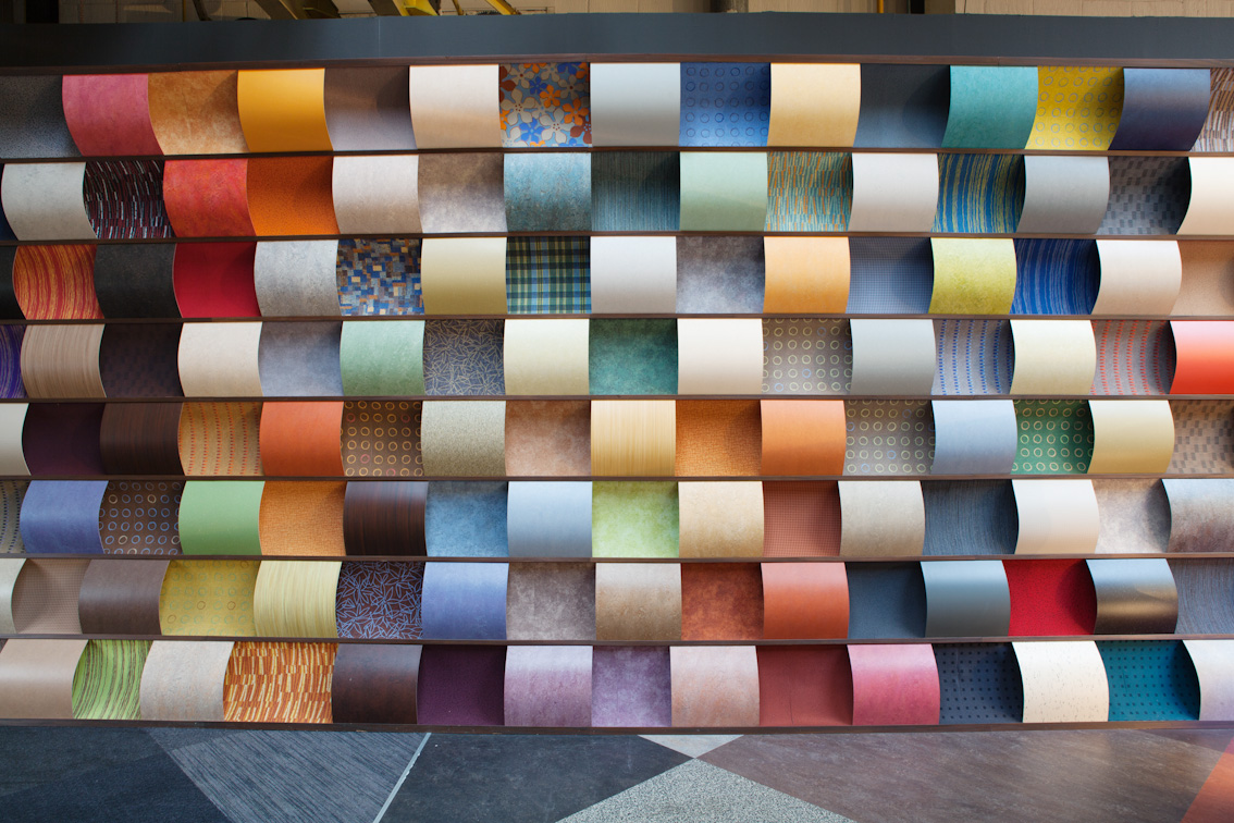 Wall display of rolled sheet flooring samples in dozens of colors and patterns