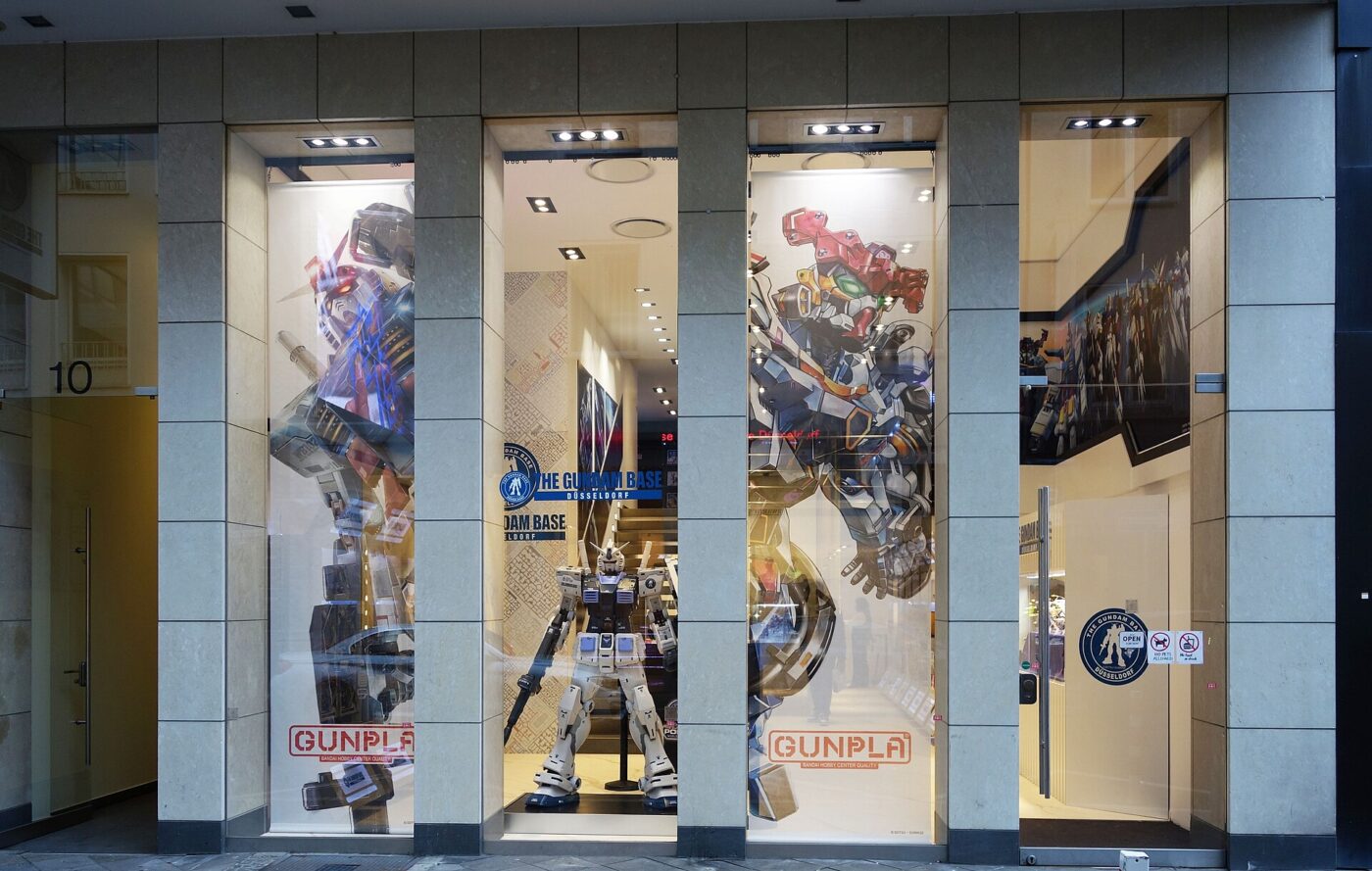 Shop windows decorated with large Gundam robot artwork, Gunpla signs and a standing robot model