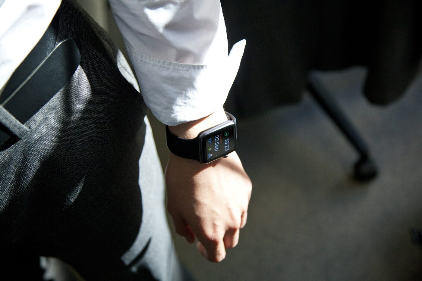 A smartwatch with a lit display worn on the wrist of a person in a white dress shirt