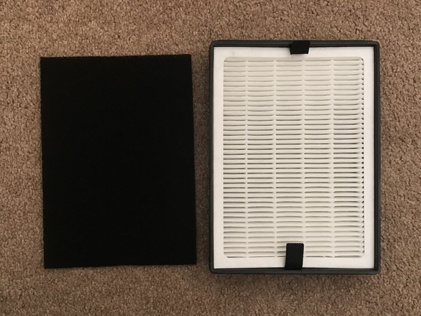 A black foam pre-filter beside a pleated filter panel from a room air cleaner.