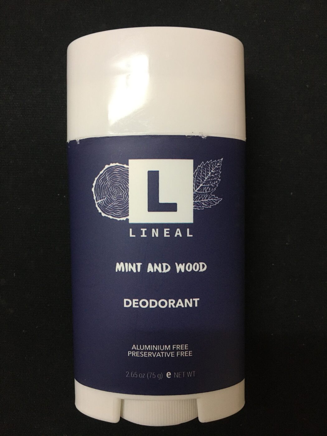 A deodorant stick labeled aluminium free and preservative free, standing on a dark surface