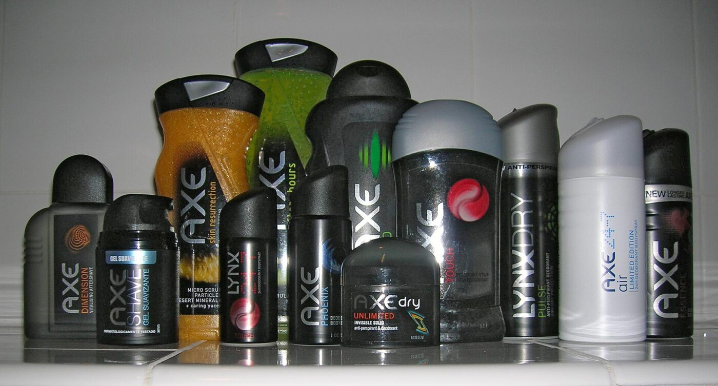 A lineup of men's body sprays, deodorant sticks and shower gels on a shelf