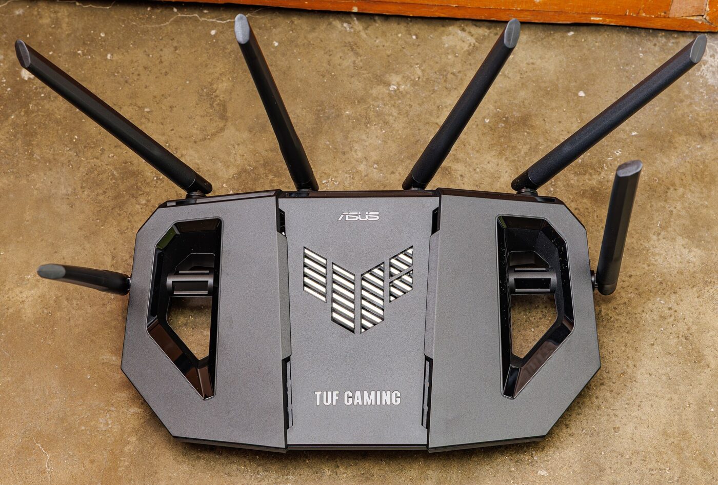 A black ASUS TUF Gaming Wi-Fi router with six antennas, photographed from above on a floor