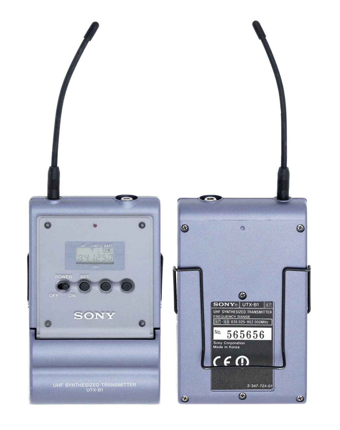 A belt-pack UHF transmitter shown front and back, with its frequency range printed on the label.