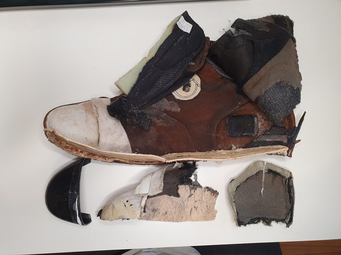 A work boot cut in half, showing the toe cap, insole layers and sole