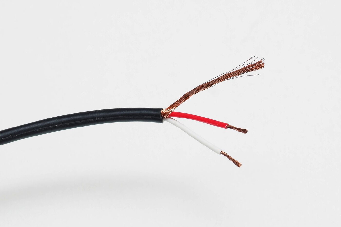 A microphone cable stripped back to show its copper shield and two insulated conductors.