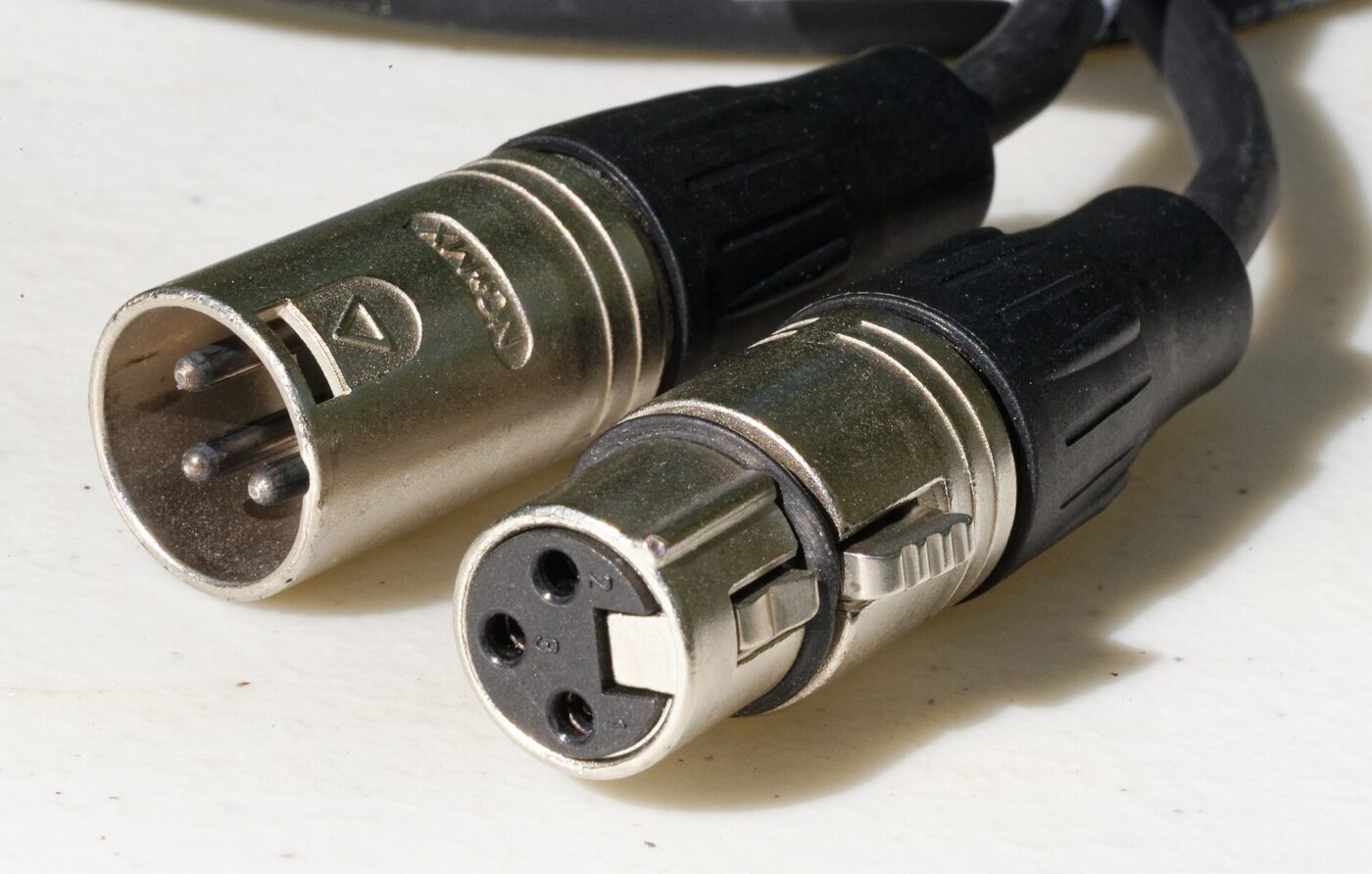 Male and female three-pin XLR connectors on the ends of two microphone cables.