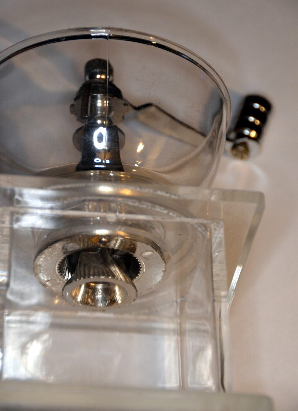 The conical burr mechanism of a coffee grinder, seen through a clear housing.