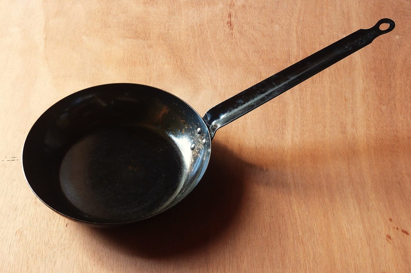An iron frying pan whose flat base is far narrower than the rim above it