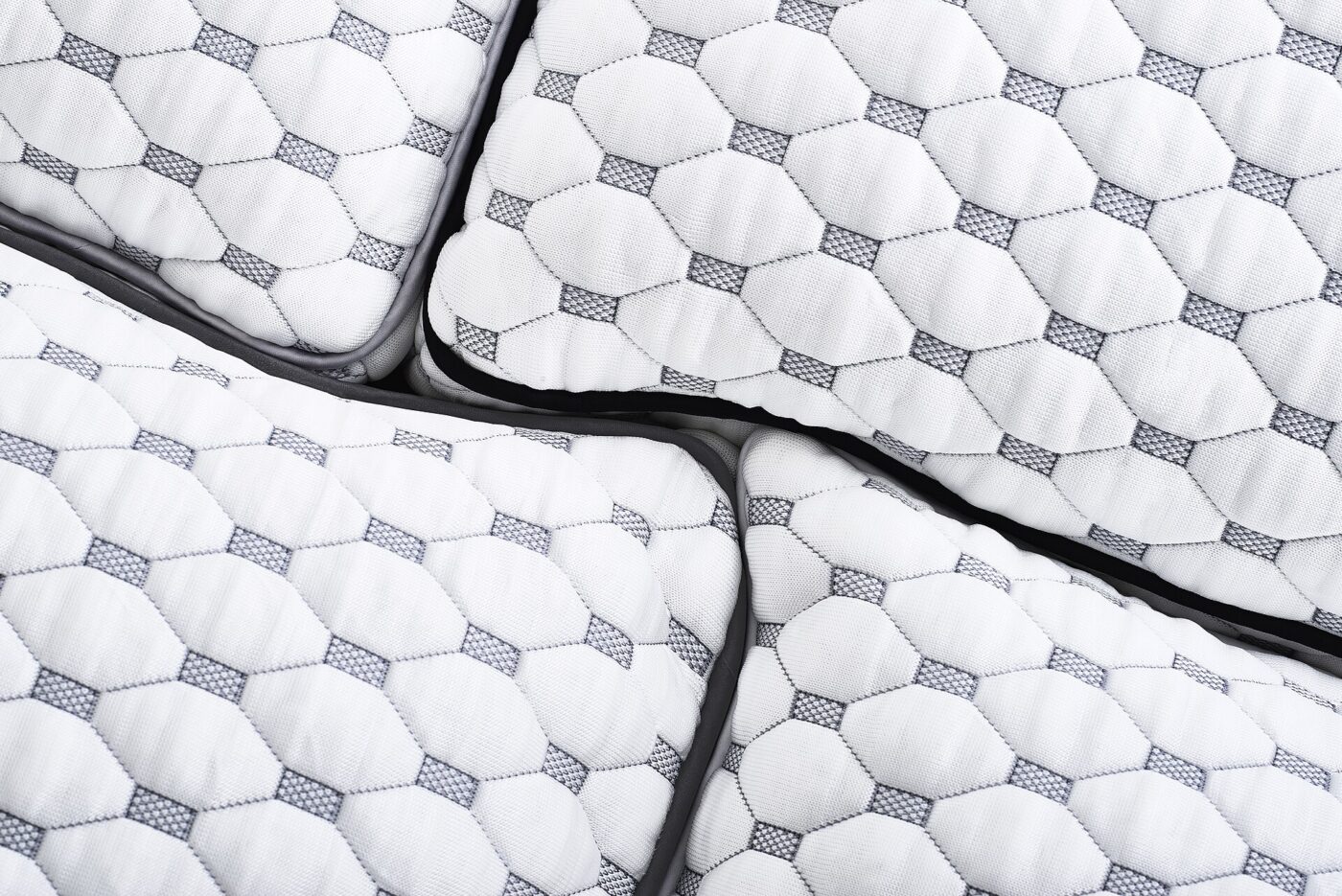 Close up of quilted white mattress covers with mesh panels along the side edges.