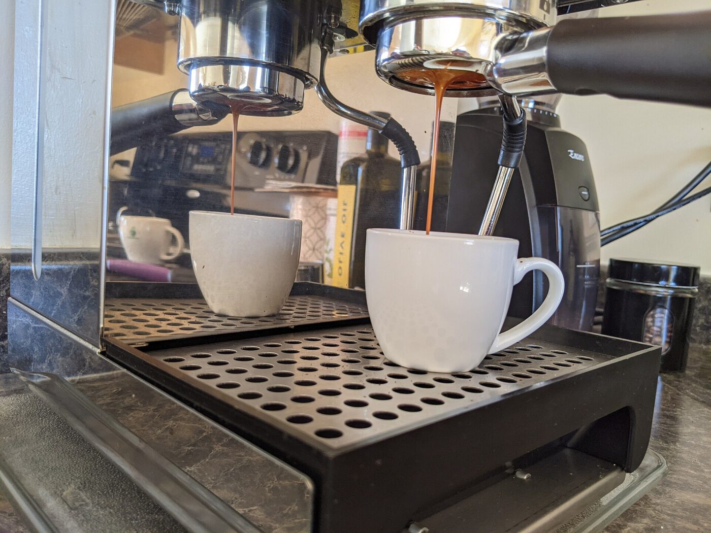 Espresso running from a bottomless portafilter into a cup, with the basket in view.