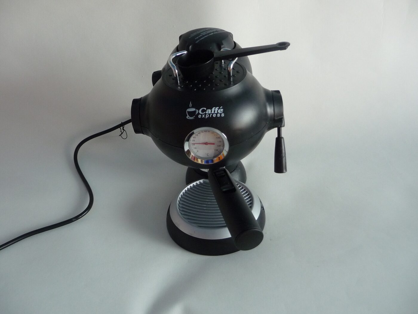 A small countertop espresso maker with a steam wand on its side for frothing milk.