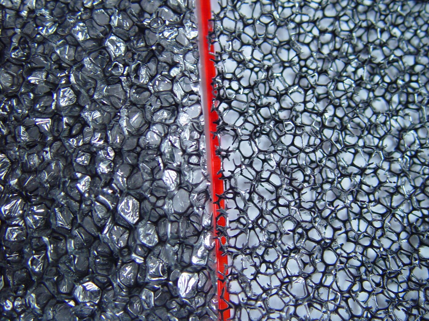 A magnified view of two foam samples with different cell structures, separated by a red marker.
