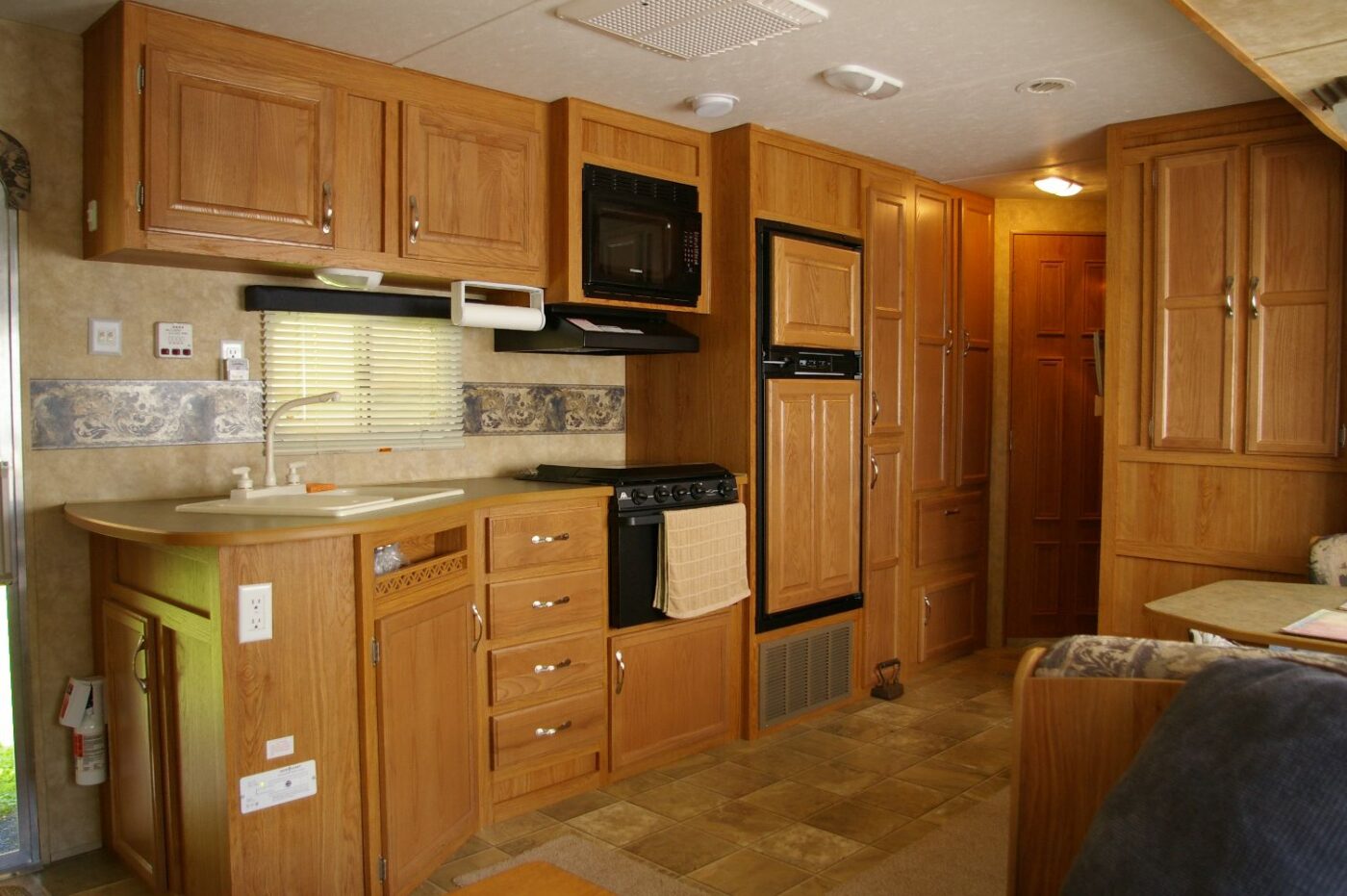A camper kitchen with a built-in range and oven below a microwave and overhead cabinets