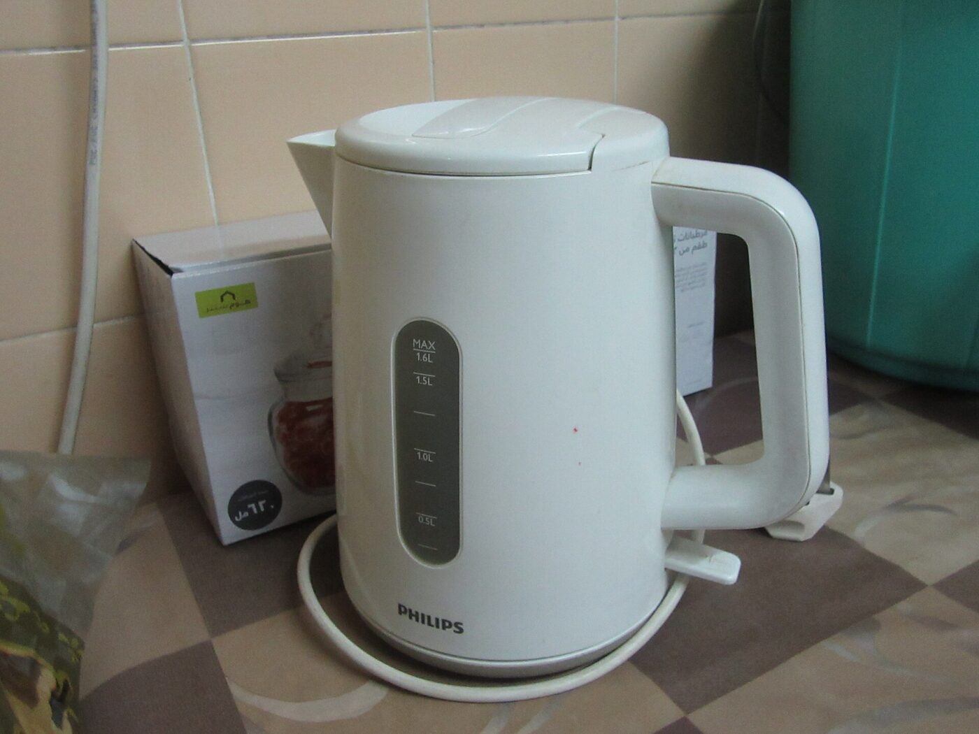 A white electric kettle on a kitchen counter, showing its moulded handle and hinged lid.