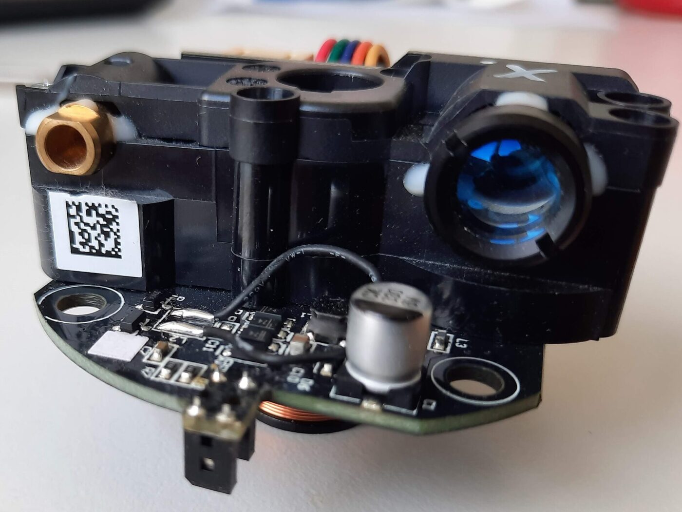 A compact spinning laser distance sensor module, with its lens and circuit board exposed.