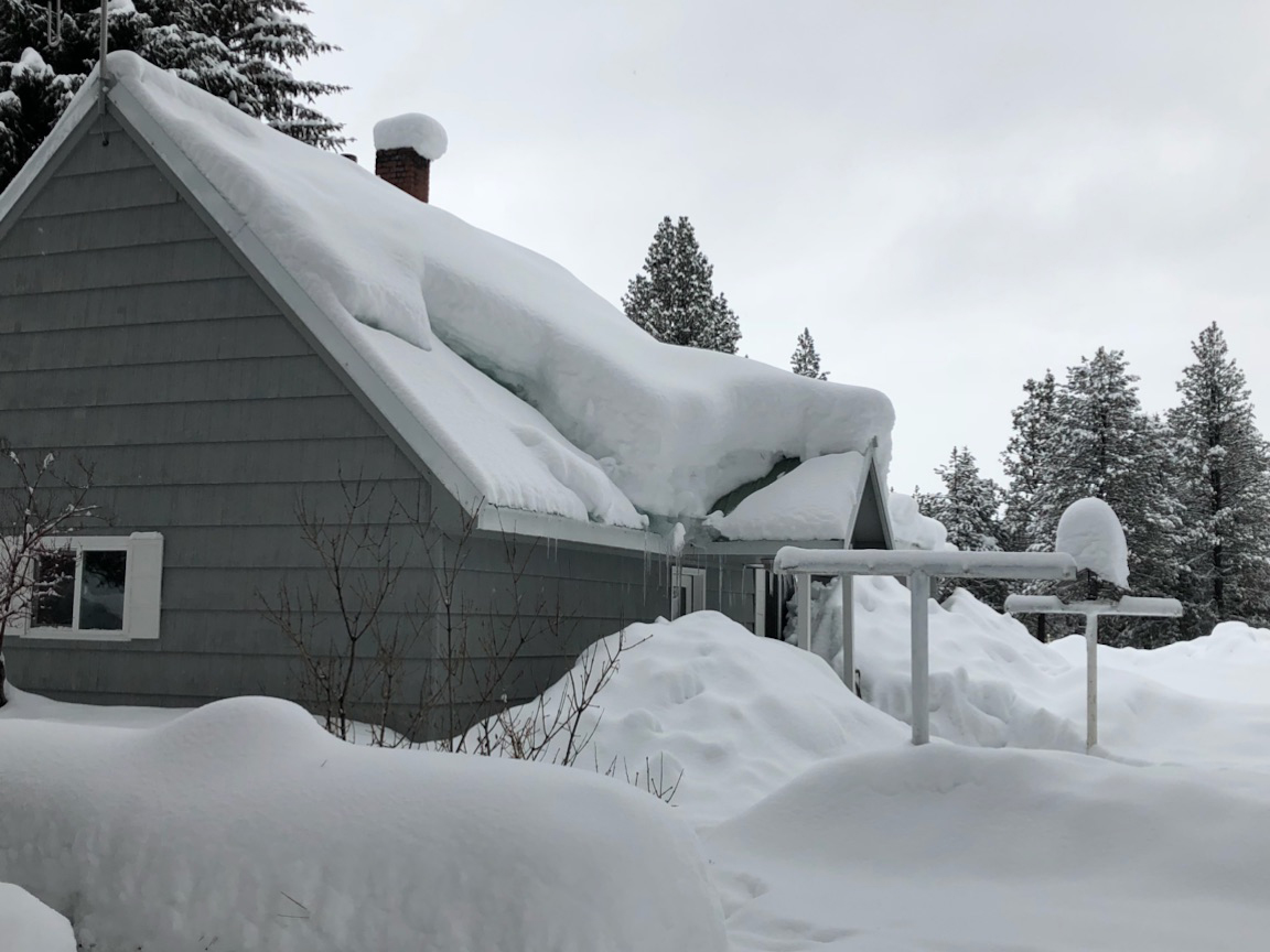 A house roof carrying a deep, even layer of settled snow