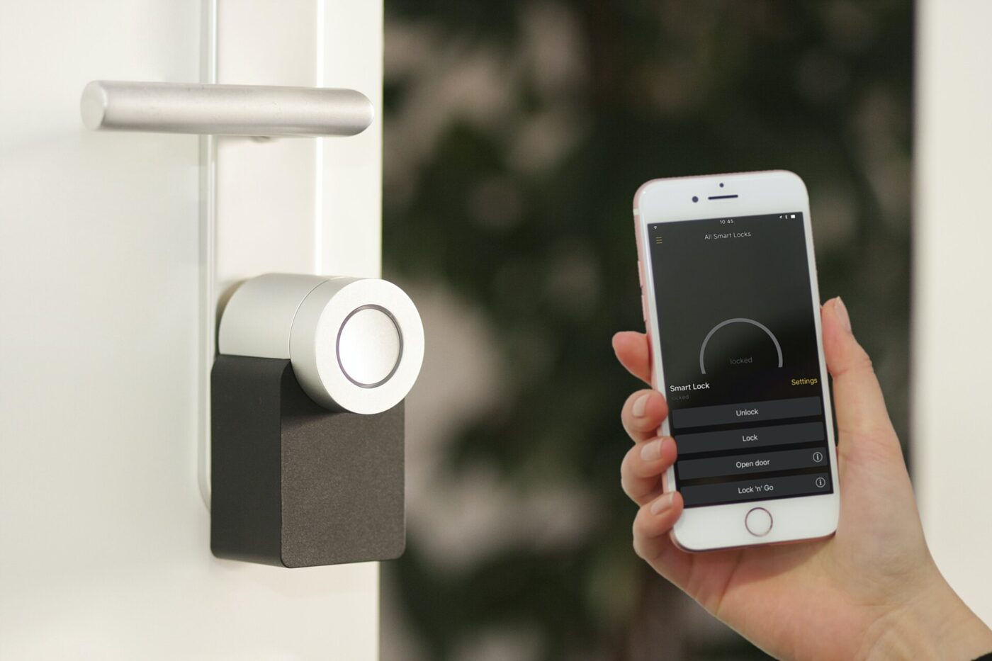 A retrofit smart lock fitted over a door's thumbturn, with its app open on a phone.