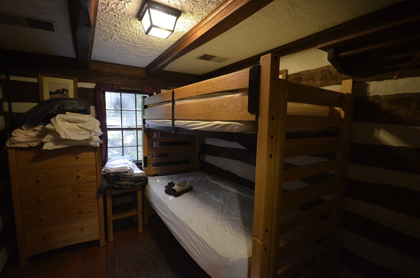 Bare mattresses on wooden bunk beds in a knotty pine cabin bedroom
