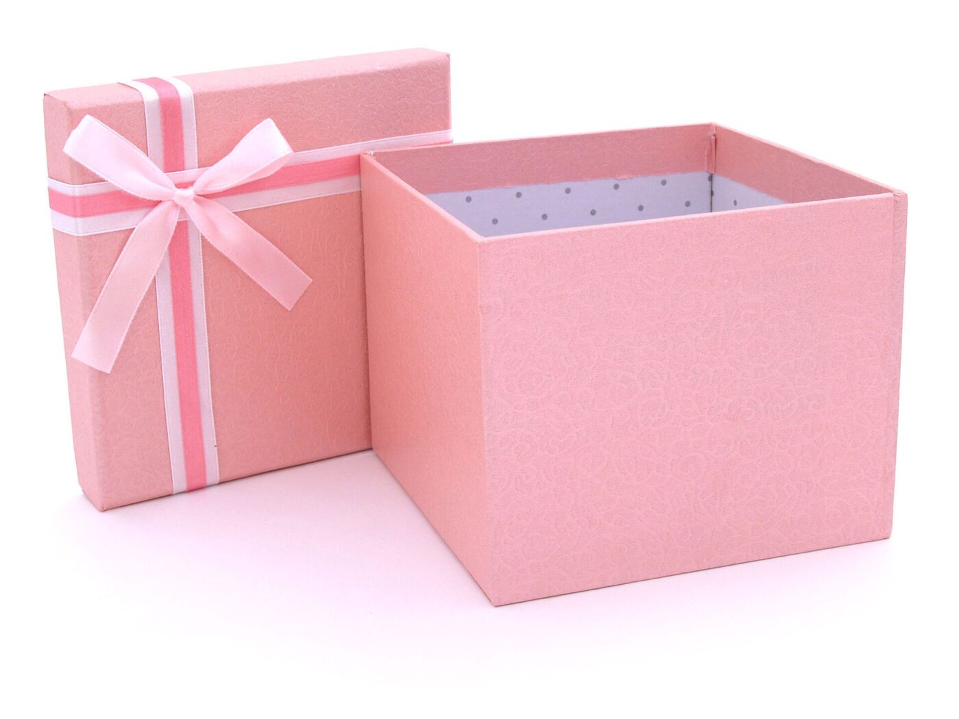 An open pink gift box with its ribboned lid set beside it on a white surface.